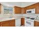Kitchen featuring wooden cabinets, white appliances, and a corner sink with natural light at 6017 Riva Ridge Dr, Indianapolis, IN 46237