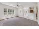 A spacious living room area with neutral carpet, white walls, and bright, natural light from the windows at 6017 Riva Ridge Dr, Indianapolis, IN 46237