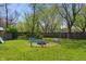 Backyard features a firepit with benches, green grass and surrounding trees at 615 W Stop 11 Rd, Indianapolis, IN 46217