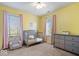 Yellow bedroom with a crib, grey dresser, chair and windows with pink curtains at 6211 W Bayfront Shores, McCordsville, IN 46055
