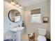 Stylish bathroom with a pedestal sink, round mirror, and natural light from the window at 6220 Yellow Birch Ct, Avon, IN 46123