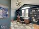 Modern home office featuring built-in bookshelves, large window, stylish chandelier and patterned area rug at 6220 Yellow Birch Ct, Avon, IN 46123