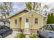 Charming home with yellow siding, white trim, front steps, and driveway with two cars at 637 Berkley Rd, Indianapolis, IN 46208