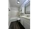 Bathroom with white tiled shower, matching vanity, white cabinets, and dark wood-look floors at 6458 Lupine Ter, Indianapolis, IN 46224