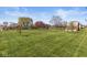Spacious backyard featuring a well-manicured lawn, mature trees, and a charming red barn at 7280 E Patricia Dr, Camby, IN 46113