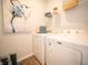 Neat laundry area with washer, dryer, shelving, storage containers, and an abstract art piece at 8502 Hemingway Dr, Indianapolis, IN 46239
