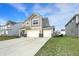 Tan two-story house with a three-car garage, surrounded by green lawns at 8583 Strabet Dr, Pendleton, IN 46064