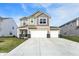 Two-story home featuring a three-car garage, tan siding, and a well-maintained lawn at 8583 Strabet Dr, Pendleton, IN 46064