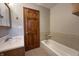 Bathroom featuring tiled flooring, a bathtub, and a wooden door with towel racks at 10586 W School Pkwy, Carmel, IN 46280