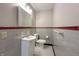 Bathroom with a red accent tile, sink, toilet, mirror, and black-and-white tile flooring at 10586 W School Pkwy, Carmel, IN 46280