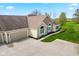 Aerial view of a home with a three car garage, stone accents, manicured lawn, and ample parking space at 1098 Extraordinary Trl, Greenfield, IN 46140