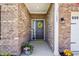 A welcoming front porch with decorative wreath, potted plants, and brick accents at 122 Winding Brook Way, Pendleton, IN 46064