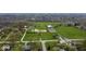 Aerial view of a property highlighting expansive green fields and surrounding wooded areas at 1221 S Catherwood Ave, Indianapolis, IN 46203