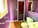 A purple bathroom with a green toilet and sink and worn-out flooring at 1221 S Catherwood Ave, Indianapolis, IN 46203