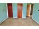 A simple bedroom with a blue wall, two doors, and worn-out flooring at 1221 S Catherwood Ave, Indianapolis, IN 46203