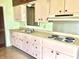 Vintage kitchen featuring pink cabinets, laminate countertops, and standard appliances, offering renovation potential at 1221 S Catherwood Ave, Indianapolis, IN 46203