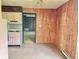 View from kitchen showcasing wood-paneled walls and a glimpse into adjacent rooms, awaiting updates at 1221 S Catherwood Ave, Indianapolis, IN 46203
