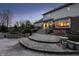 Backyard view featuring a brick patio, hot tub, and lush landscaping at dusk at 12715 Norfolk Ln, Carmel, IN 46032