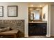 Elegant bathroom featuring a dark wood vanity, granite countertop, decorative mirror, and earth-tone tile accent wall at 12715 Norfolk Ln, Carmel, IN 46032
