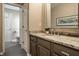 Stylish bathroom showcasing a granite countertop vanity, decorative mirror, and an open doorway to the toilet area at 12715 Norfolk Ln, Carmel, IN 46032