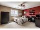 Cozy bedroom features neutral carpet, red accent wall, ceiling fan, and a neatly made bed with decorative pillows at 12715 Norfolk Ln, Carmel, IN 46032