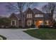 Elegant brick home with a well-lit entrance, manicured lawn, and mature trees creating a serene atmosphere at 12715 Norfolk Ln, Carmel, IN 46032