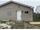 Exterior view of the home featuring a white door, tan siding, and boarded window at 1309 W Memorial Dr, Muncie, IN 47302