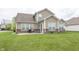 Rear exterior view of a well-maintained home with a concrete patio, brick accents, and expansive grassy backyard at 14014 Fieldcrest Dr, McCordsville, IN 46055