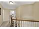Upstairs hallway featuring wood railing, carpeted floor, and view into a bedroom at 1611 Connemara Rd, Indianapolis, IN 46217