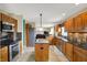 An open kitchen with stainless appliances, wood cabinets, dark countertops, and a center island offers ample space at 1611 Connemara Rd, Indianapolis, IN 46217
