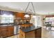 A well-lit kitchen with a dark countertop island, wood cabinets, and stainless steel appliances enhances the home at 1611 Connemara Rd, Indianapolis, IN 46217
