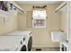 Functional laundry room with a washer, dryer, sink, and shelving for storage and organization at 1611 Connemara Rd, Indianapolis, IN 46217