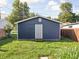 View of blue detached garage with a back door and steps overlooking the yard at 1613 E Ohio St, Indianapolis, IN 46201