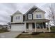 Two-story home features a two car garage, dark brown siding and cream colored accents under a cloudy sky at 17039 Silo Ridge Way, Noblesville, IN 46060