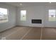 Unfinished living room with an electric fireplace, three windows, and cardboard covering the floor at 17039 Silo Ridge Way, Noblesville, IN 46060