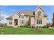 Elegant two-story home featuring stone and brick facade, arched entryway, and professionally landscaped lawn at 3384 Homestretch Dr, Carmel, IN 46032