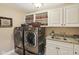 Bright laundry room featuring white cabinets, open shelving, and stainless steel washer/dryer units at 3384 Homestretch Dr, Carmel, IN 46032