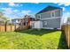 Wide shot of the backyard showing the light blue house and wooden fence under a blue sky at 3628 N Illinois St, Indianapolis, IN 46208