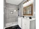 Bathroom with a tiled shower and hexagon shower floor design, a wood framed mirror, tiled walls and double sinks at 3628 N Illinois St, Indianapolis, IN 46208