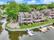An aerial view displays a row of townhomes, landscaped lawns, docks and boats by the water with clear skies and lush greenery at 3646 Beach Blvd, Cicero, IN 46034