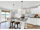 Open kitchen with white cabinetry, stainless island with barstool seating and sliding glass doors to deck at 3646 Beach Blvd, Cicero, IN 46034