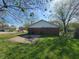 Rear view of brick home with grassy area, driveway and adjacent shed at 3755 N Brentwood Ave, Indianapolis, IN 46235