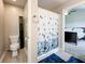 Well-lit bathroom features a toilet, built-in shelving, and a shower with a stylish blue leaf curtain at 5007 Avian Ln, Indianapolis, IN 46235