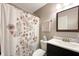 A well-lit bathroom features a toilet, vanity, sink, floral-patterned shower curtain, and a mirror at 5007 Avian Ln, Indianapolis, IN 46235