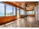Cozy sunroom featuring wood paneled walls, wood flooring, a wood burning stove and many windows at 5551 W 200 N, Greenfield, IN 46140