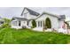 Stunning white farmhouse featuring a sunroom, manicured lawn, French doors, and elegant outdoor decor at 5682 Upper Garden Way, Zionsville, IN 46077