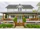 Inviting two-story home with a covered front porch, wood railing, fenced yard, and beautifully landscaped front yard at 5682 Upper Garden Way, Zionsville, IN 46077