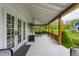 Inviting covered porch with dark-stained wood beams, dining set, and view of manicured lawn and lush green trees at 5682 Upper Garden Way, Zionsville, IN 46077