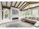 Sunroom with fireplace, wood beams, and large windows offering view of outdoor greenery and natural light at 5682 Upper Garden Way, Zionsville, IN 46077