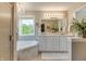 Luxurious bathroom featuring dual sinks, soaker tub under a window, and a chandelier with tile surround at 6054 Easy Ln, Indianapolis, IN 46259